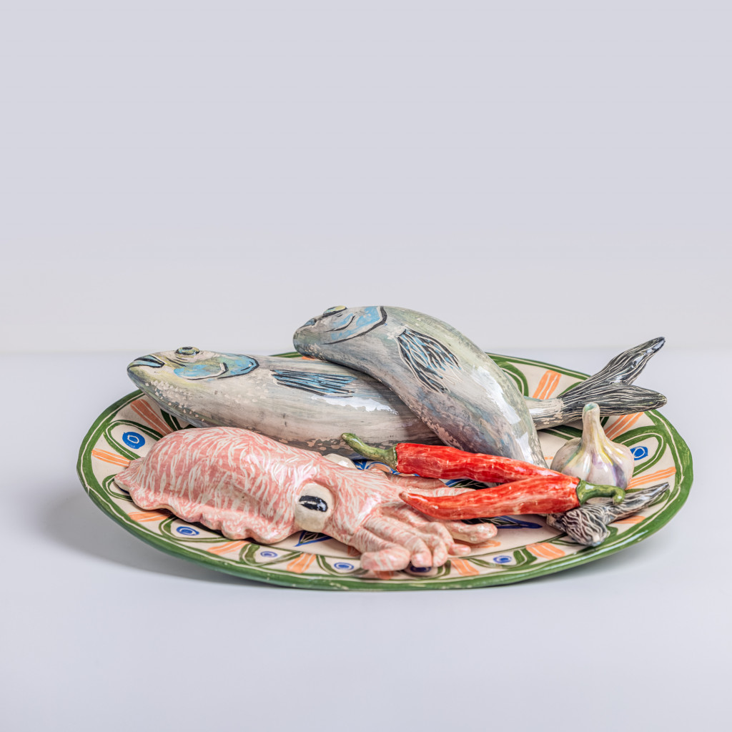 Ceramic still life with sea bass, cuttlefish, chili and a head of garlic, handmade and painted in a unique & colourful style by Spanish artist Maite Morell.