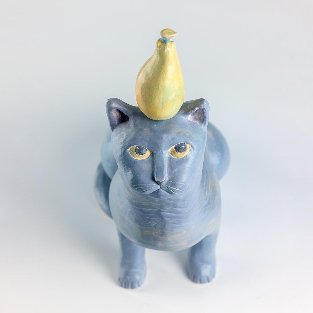 Ceramic sculpture of a cat with a pear, handmade and painted in a unique style by Spanish artist Maite Morell.
