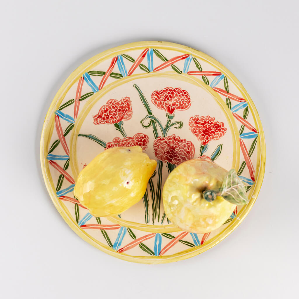 Ceramic still life of a plate of carnations and two quinces, handmade and painted in a unique & colourful style by Spanish artist Maite Morell.