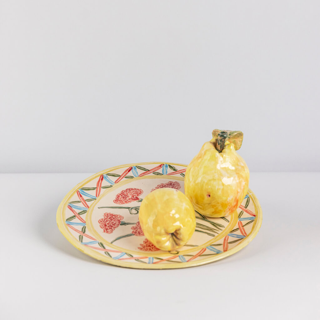 Ceramic still life of a plate of carnations and two quinces, handmade and painted in a unique & colourful style by Spanish artist Maite Morell.
