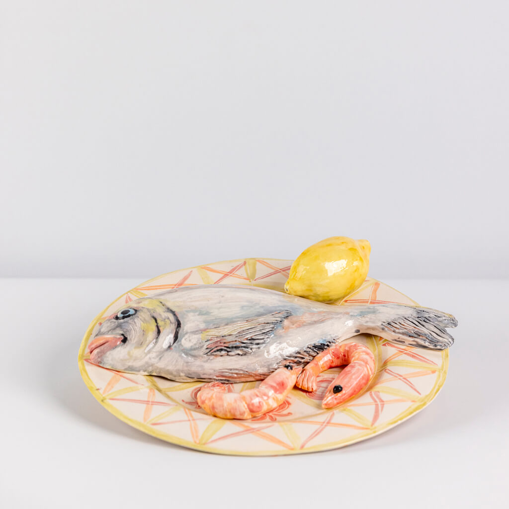 Ceramic still life of a plate of fish, prawns and lemon, handmade and painted in a unique & colourful style by Spanish artist Maite Morell.