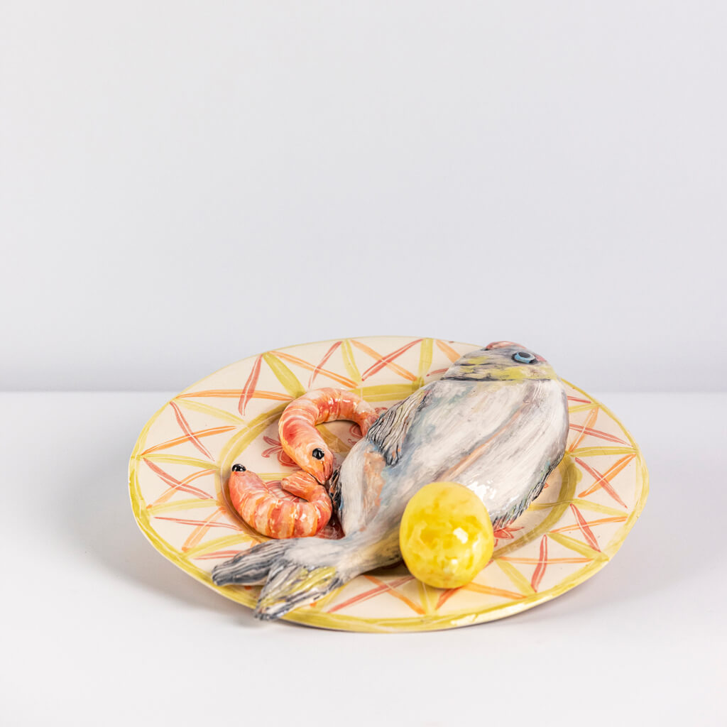 Ceramic still life of a plate of fish, prawns and lemon, handmade and painted in a unique & colourful style by Spanish artist Maite Morell.