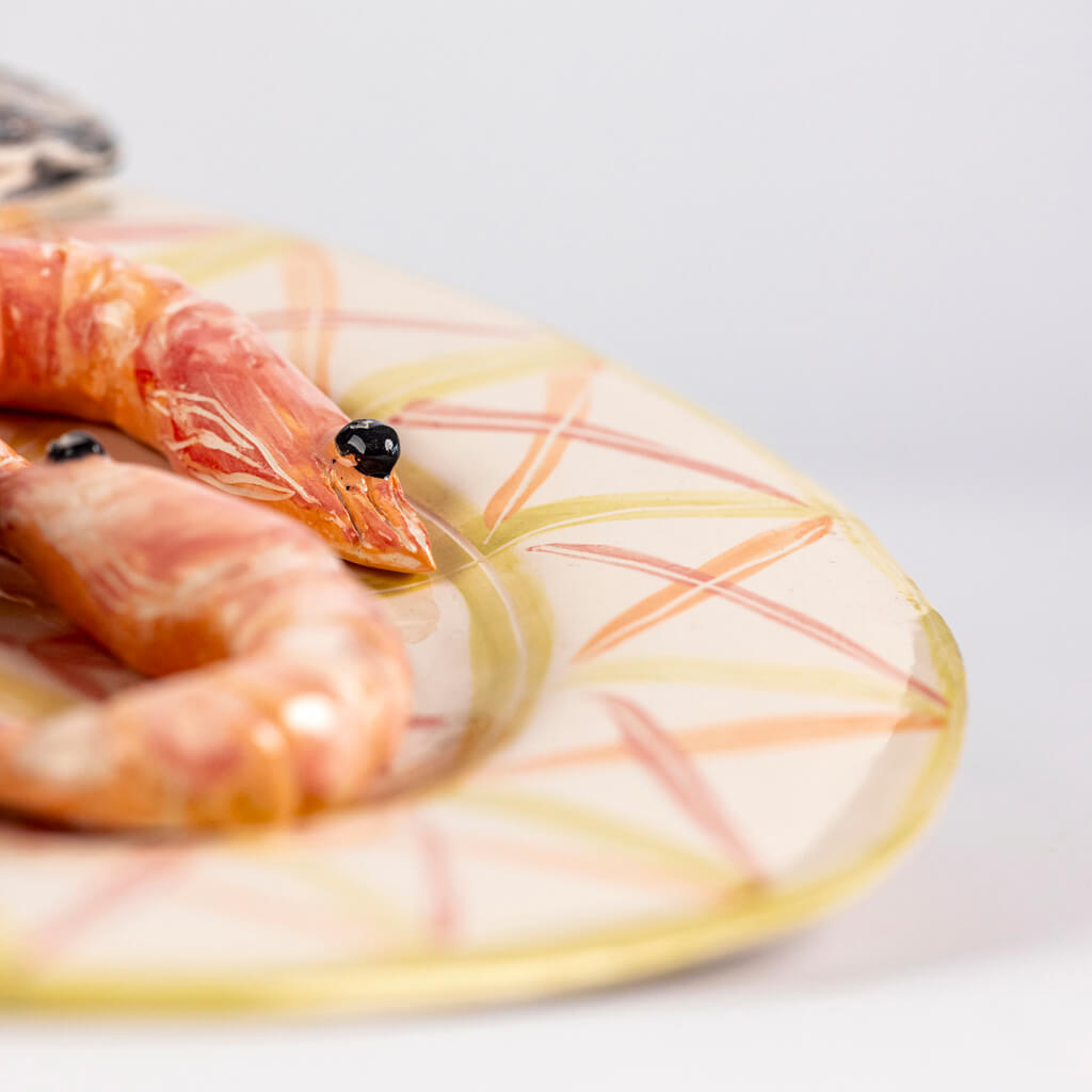 Ceramic still life of a plate of fish, prawns and lemon, handmade and painted in a unique & colourful style by Spanish artist Maite Morell.