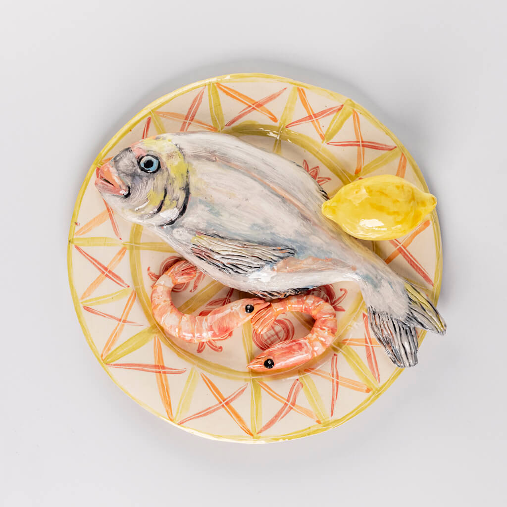 Ceramic still life of a plate of fish, prawns and lemon, handmade and painted in a unique & colourful style by Spanish artist Maite Morell.