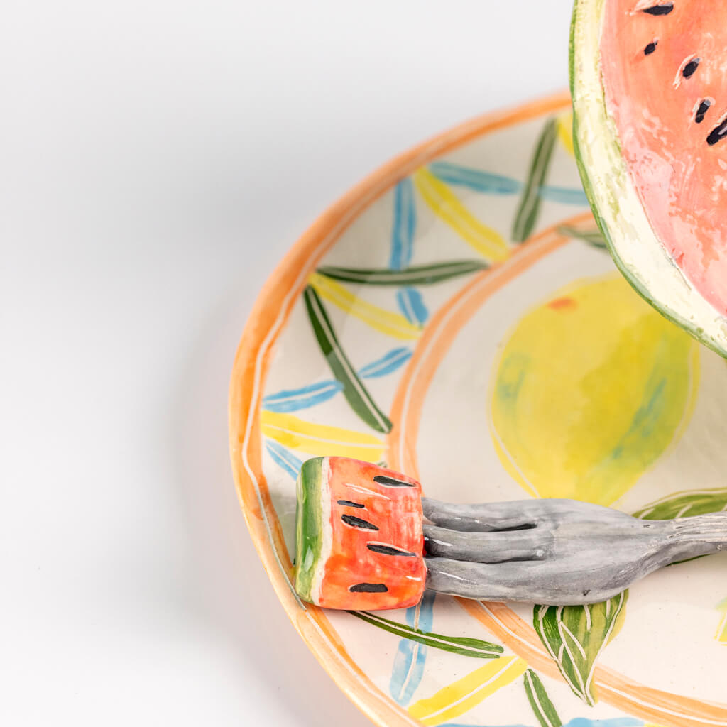 Ceramic still life of a plate of watermelon and a fork, handmade and painted in a unique & colourful style by Spanish artist Maite Morell.