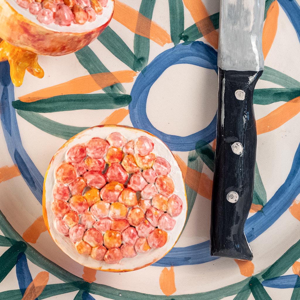 Ceramic still life with pomegranate and knife, handmade and painted in a unique style by Spanish artist Maite Morell.