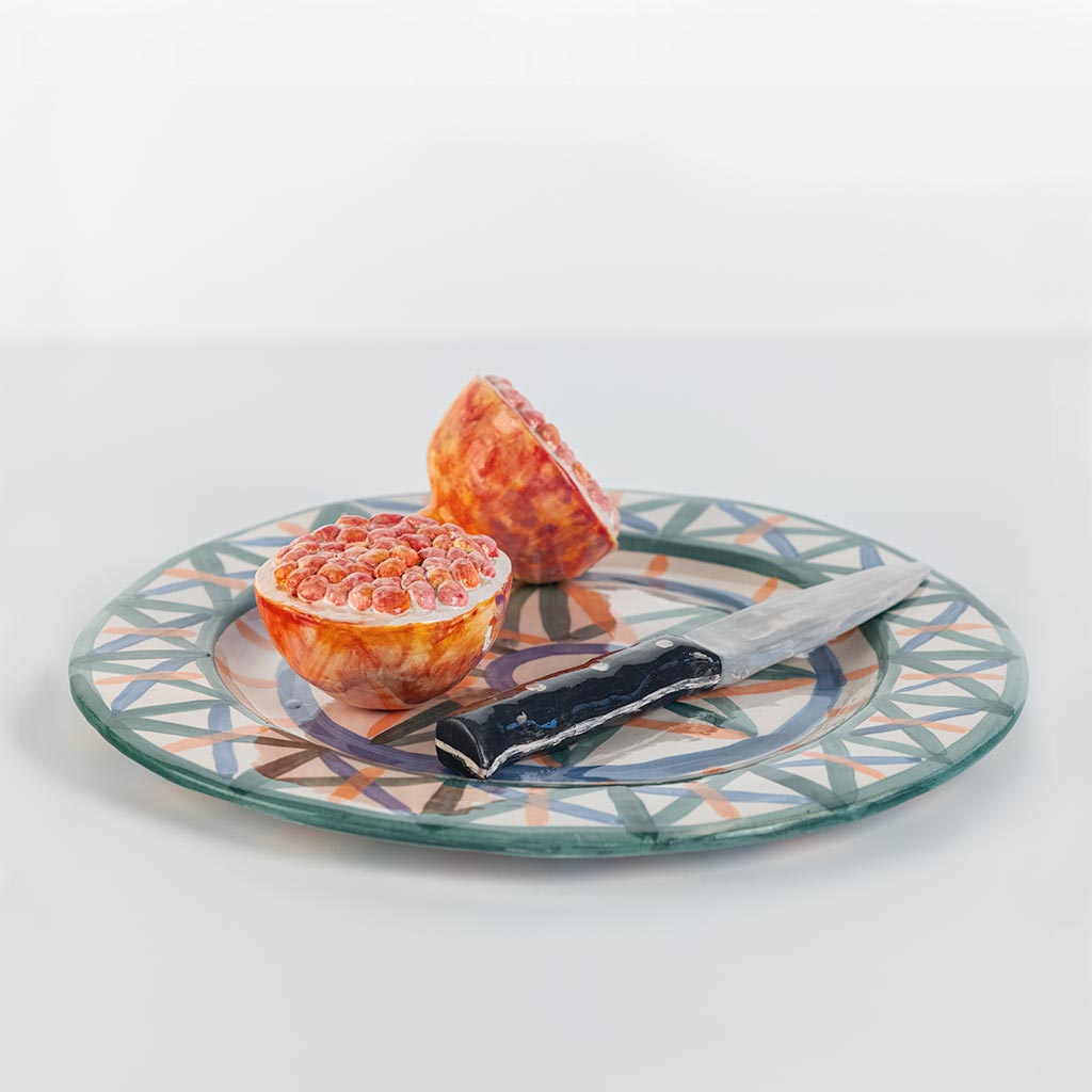 Ceramic still life with pomegranate and knife, handmade and painted in a unique style by Spanish artist Maite Morell.