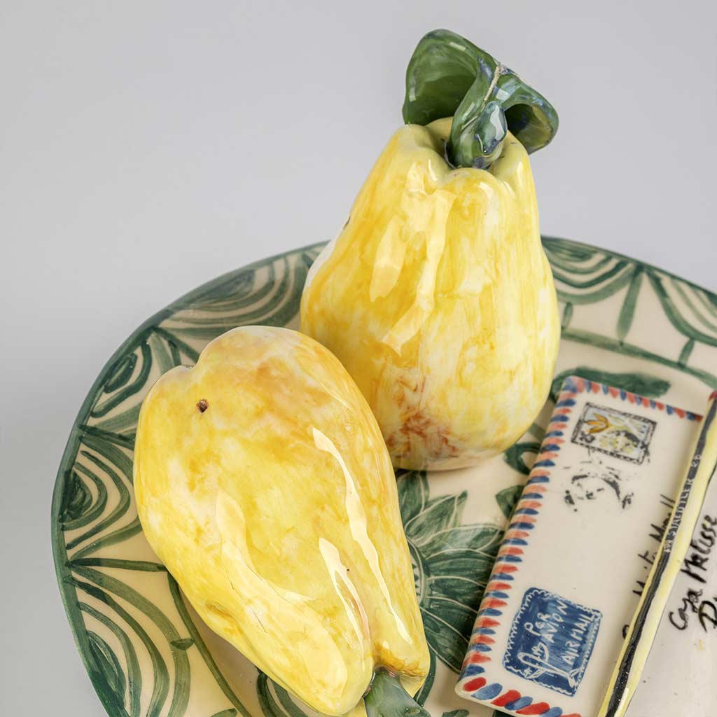 Ceramic still life of a green plate with a quince and a love letter, handmade and painted in a unique style by Spanish artist Maite Morell.