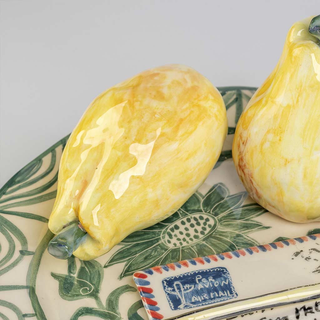 Ceramic still life of a green plate with a quince and a love letter, handmade and painted in a unique style by Spanish artist Maite Morell.