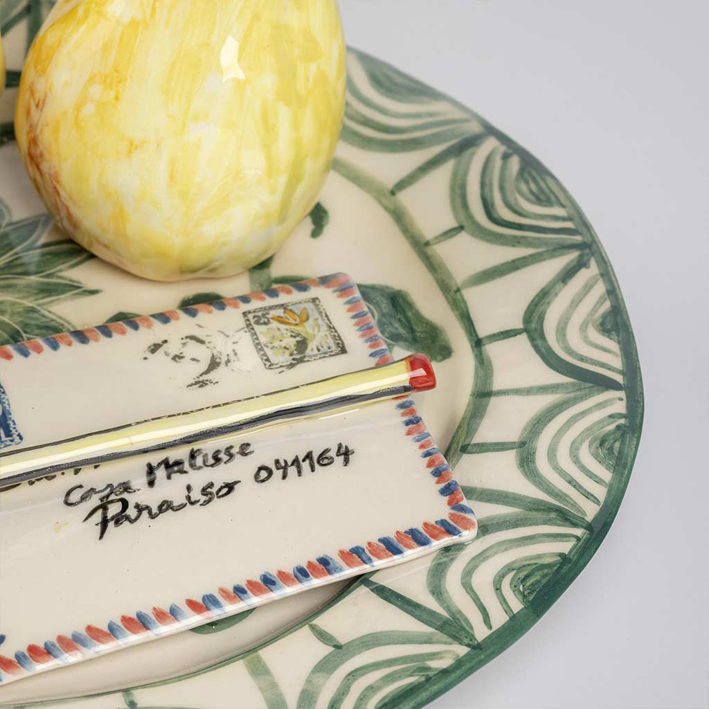 Ceramic still life of a green plate with a quince and a love letter, handmade and painted in a unique style by Spanish artist Maite Morell.
