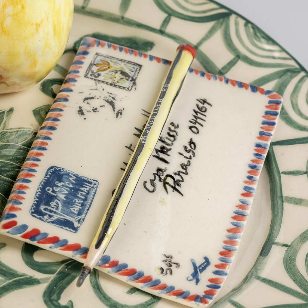 Ceramic still life of a green plate with a quince and a love letter, handmade and painted in a unique style by Spanish artist Maite Morell.