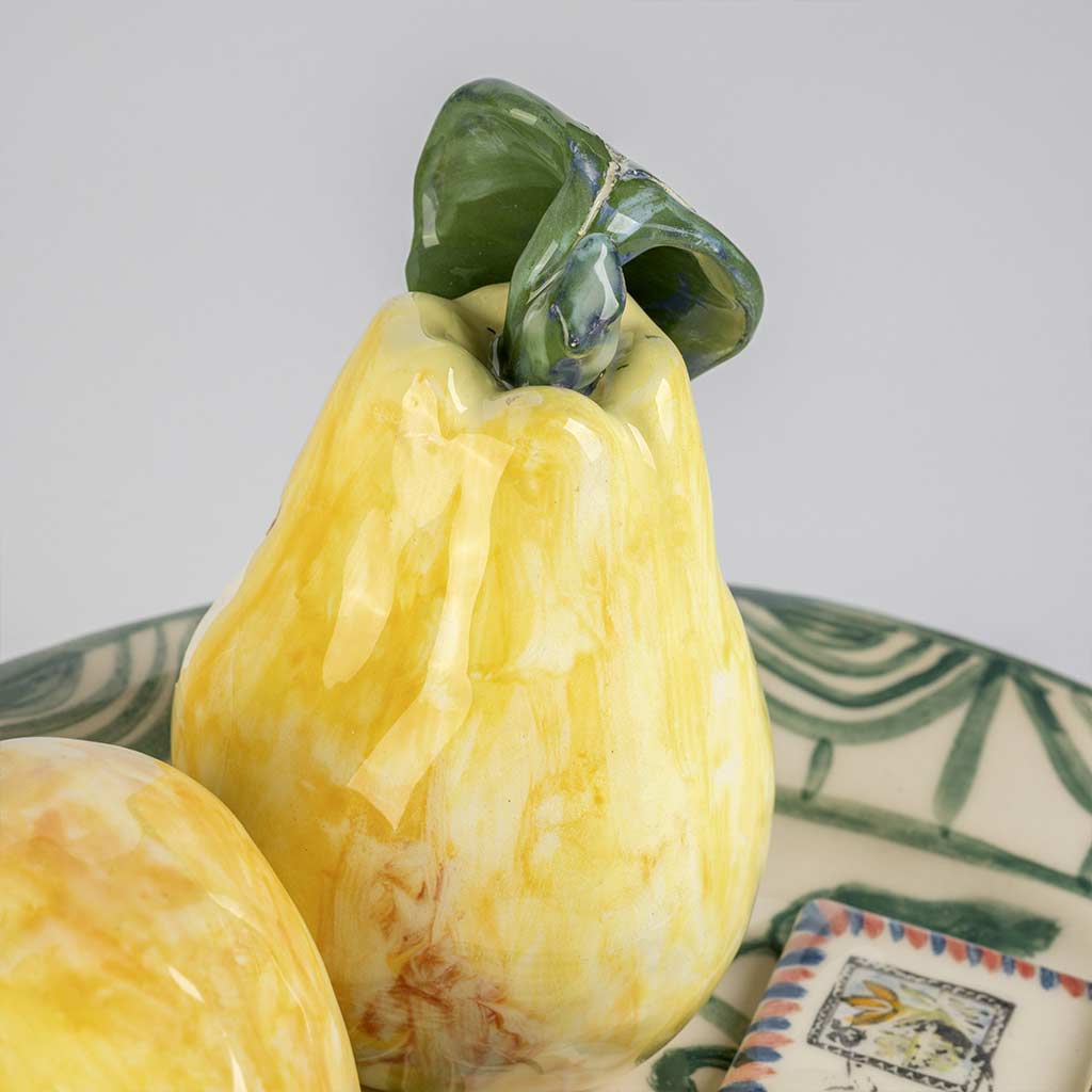 Ceramic still life of a green plate with a quince and a love letter, handmade and painted in a unique style by Spanish artist Maite Morell.