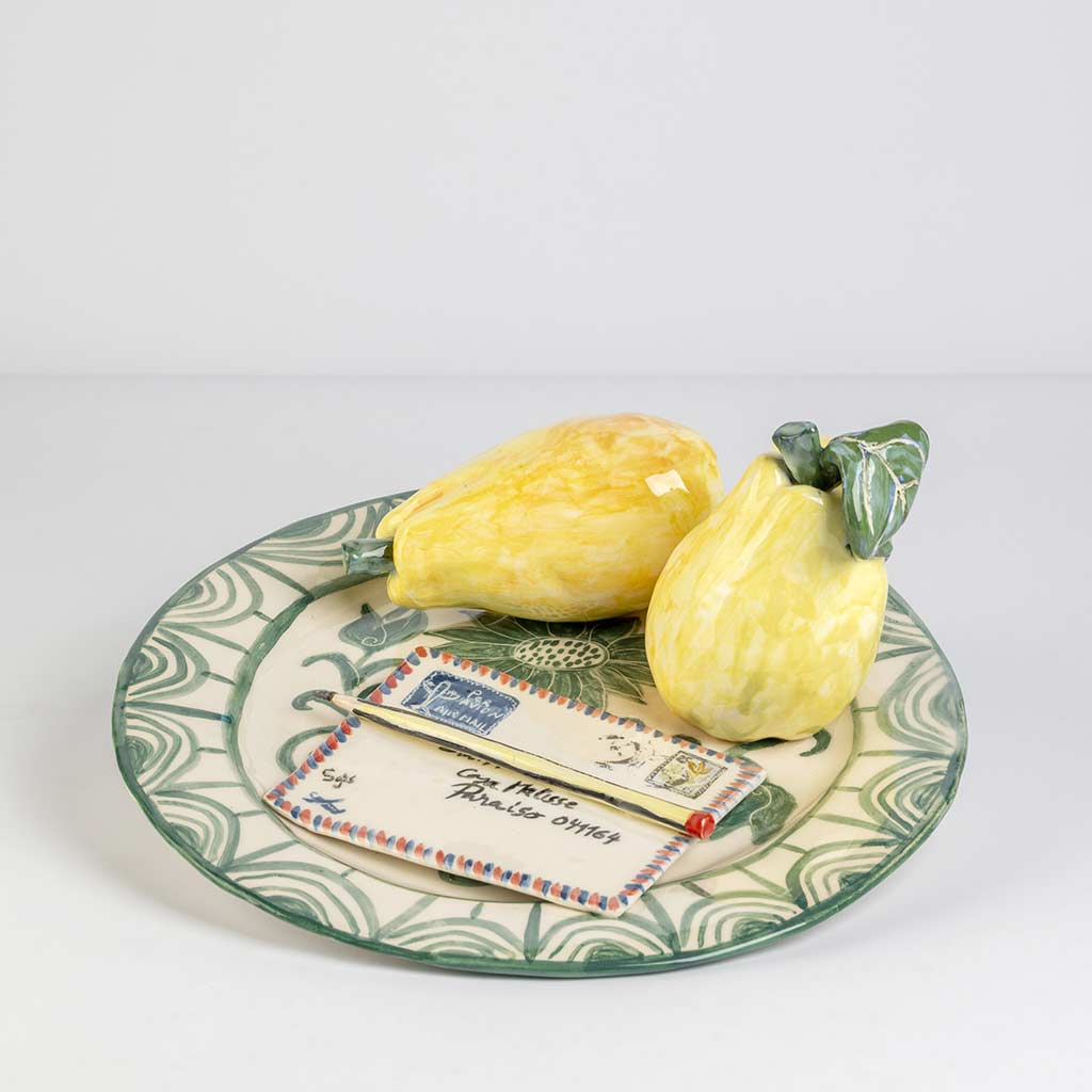 Ceramic still life of a green plate with a quince and a love letter, handmade and painted in a unique style by Spanish artist Maite Morell.