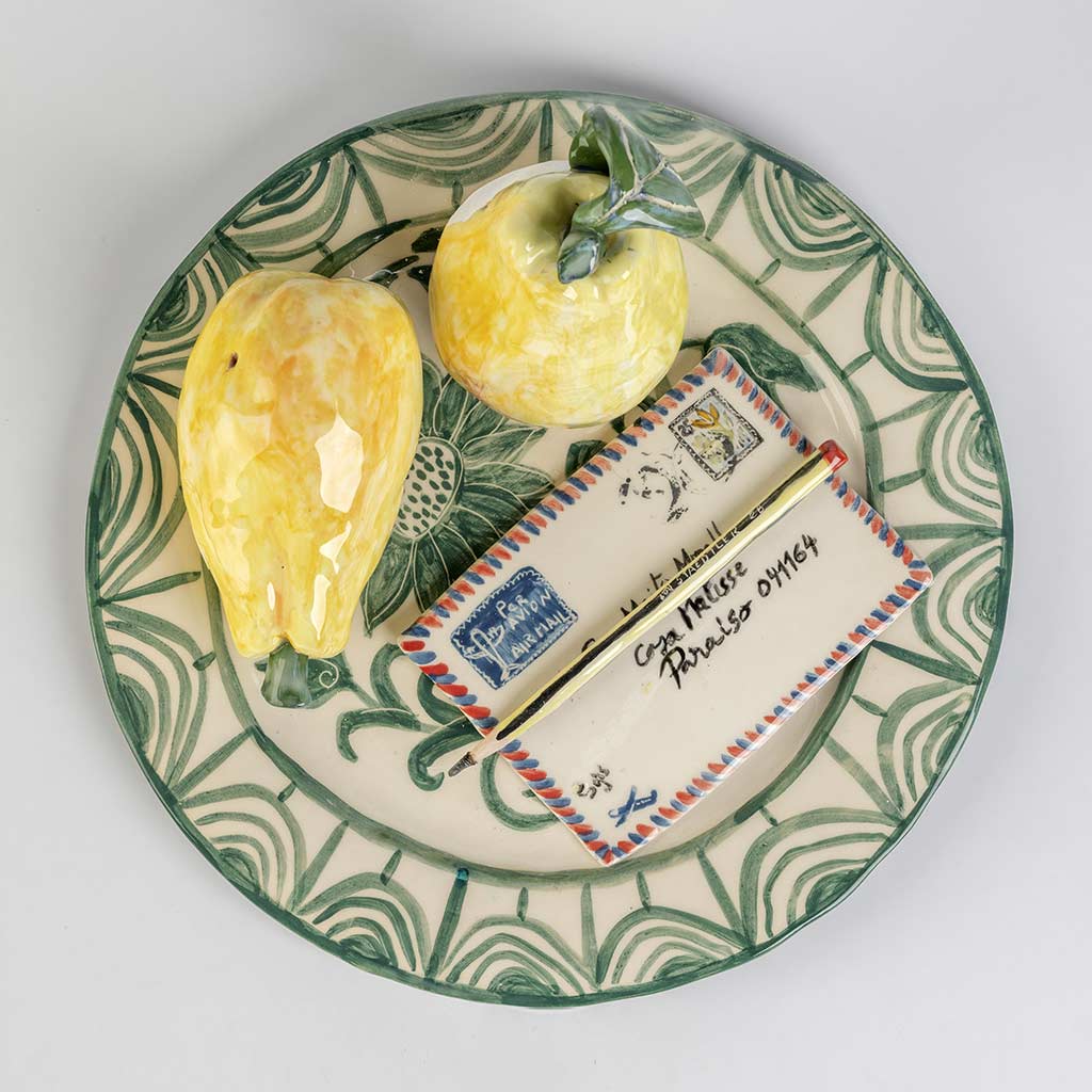 Ceramic still life of a green plate with a quince and a love letter, handmade and painted in a unique style by Spanish artist Maite Morell.
