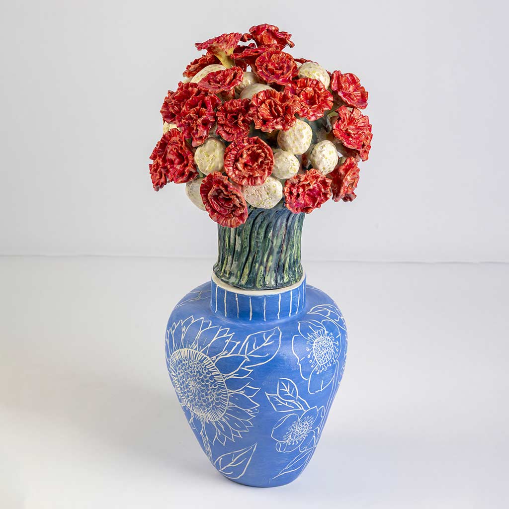 Ceramic still life of a klein blue vase with red carnations, handmade and painted in a unique style by Spanish artist Maite Morell.