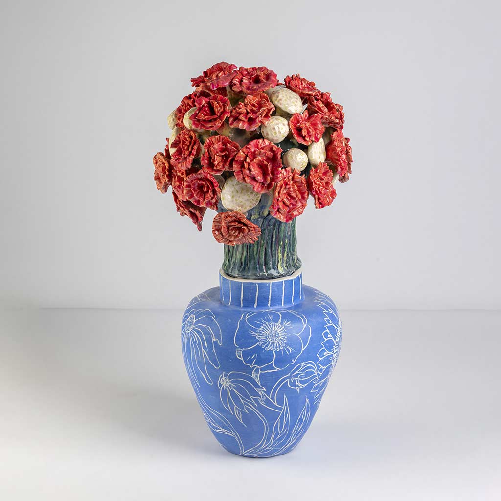 Ceramic still life of a klein blue vase with red carnations, handmade and painted in a unique style by Spanish artist Maite Morell.